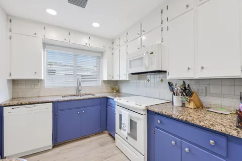a kitchen with granite countertop a sink a stove and cabinets