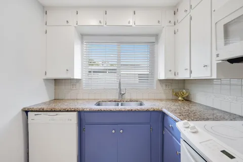 a kitchen with granite countertop white cabinets and a sink