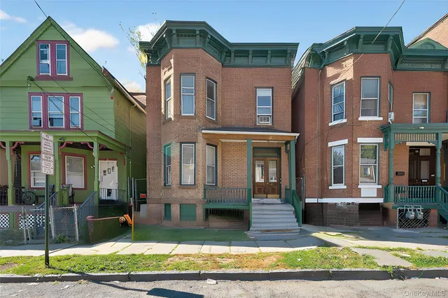a view of a brick house with many windows and a yard