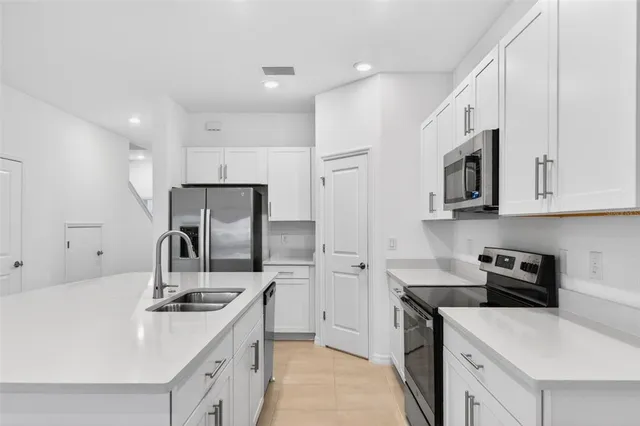 a kitchen with stainless steel appliances a sink stove refrigerator and cabinets