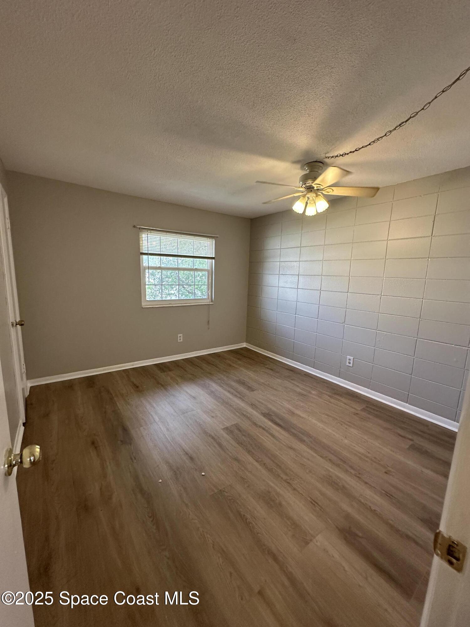 55 Needle Boulevard, Unit 57 Merritt Island, FL 32953 - Photo 10 of 12 an empty room with wooden floor and windows
