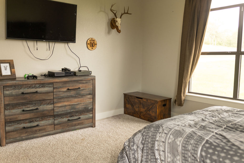 111 Powder Ridge Luling, TX 78648 - Photo 5 of 22 Comfortable bedroom with carpeted flooring and ample natural light from a large window.