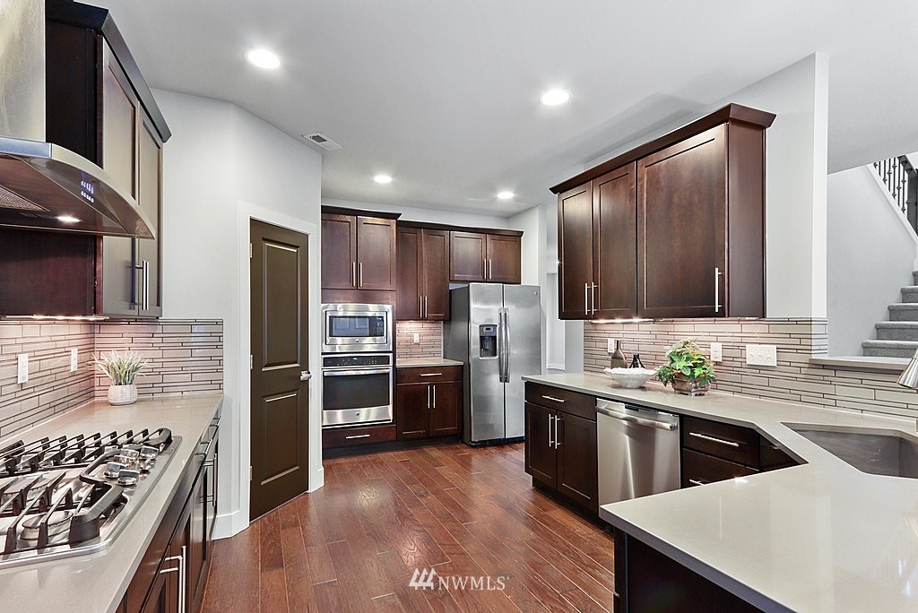 16808 1st Avenue West Bothell, WA 98012 - Photo 11 of 29 a kitchen with stainless steel appliances kitchen island granite countertop a stove a sink dishwasher a refrigerator and cabinets with wooden floor