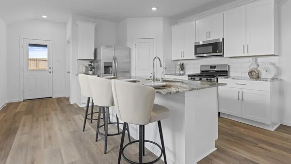 a kitchen with stainless steel appliances a stove a sink a refrigerator cabinets and wooden floor