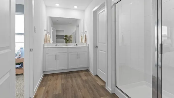 a view of a hallway and wooden floor and a bathroom