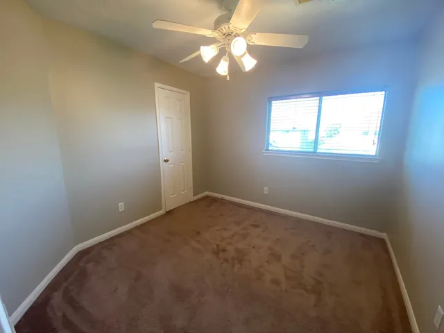 an empty room with windows and fan