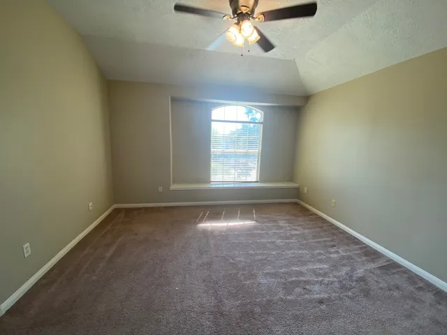 an empty room with a window and a fan