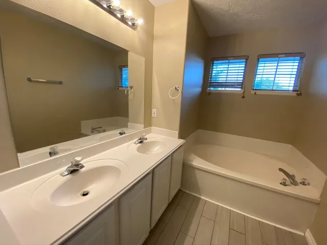 a bathroom with a tub a sink and mirror
