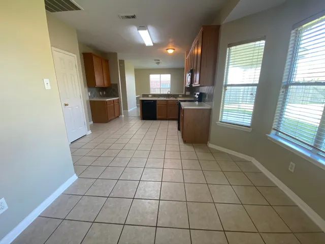a kitchen with granite countertop a refrigerator a stove top oven and sink