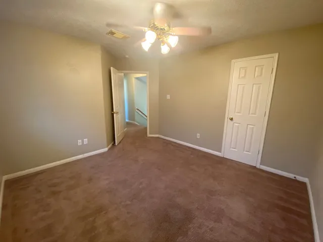 an empty room with a chandelier fan and closet