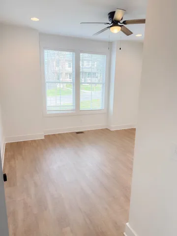 an empty room with a window and a fan