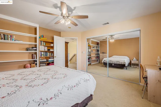 a bedroom with a bed a chair and potted plant on the dresser