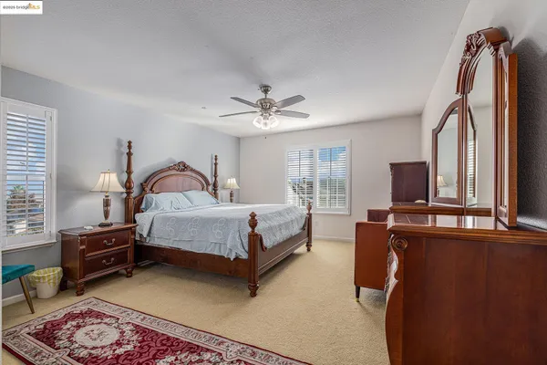 a spacious bedroom with a bed and ceiling fan