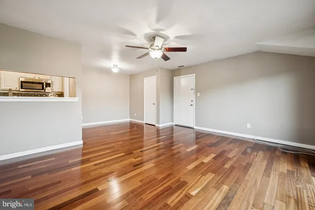 a view of empty room with wooden floor and fan
