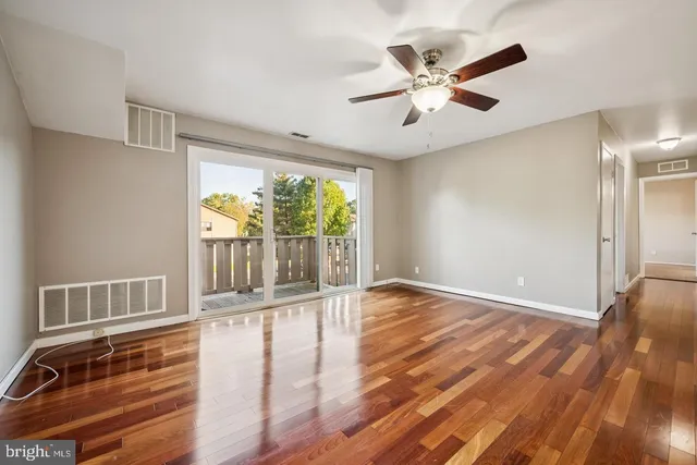 an empty room with wooden floor and fan