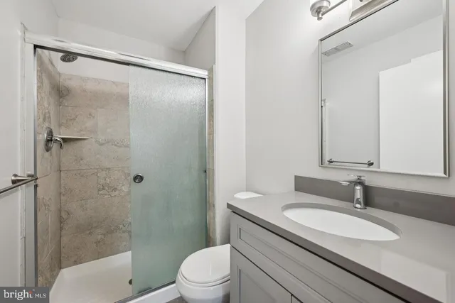 a bathroom with a granite countertop sink toilet and shower