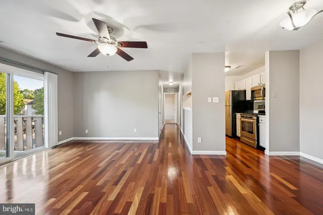 a view of empty room with wooden floor and fan