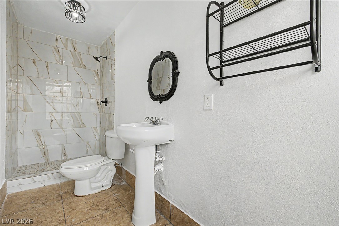 5357 Indian Wells Road Las Vegas, NV 89110 - Photo 34 of 39 A streamlined bathroom offers a tiled shower and pedestal sink, creating a minimalist yet functional space.