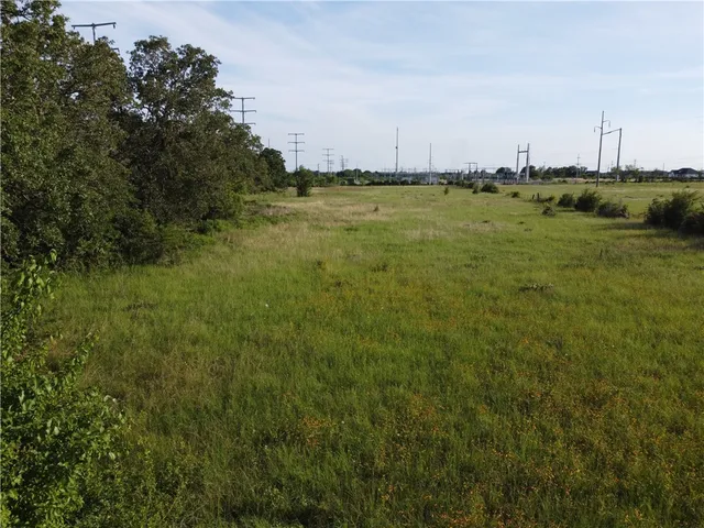 a view of a green field with lots of trees in the background