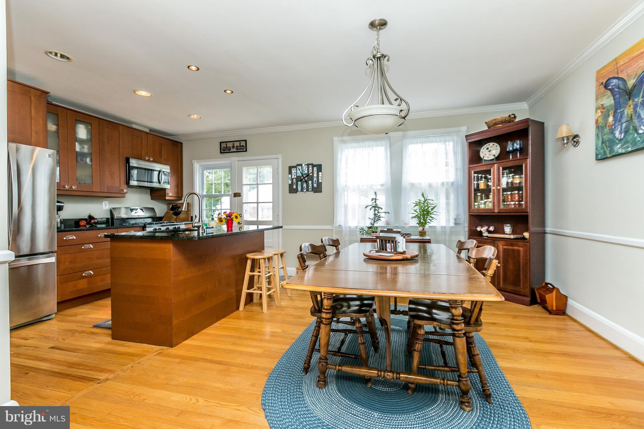 215 Dumbarton Road Baltimore, MD 21212 - Photo 6 of 30 a kitchen with stainless steel appliances granite countertop a stove a refrigerator a kitchen island a dining table and chairs with wooden floor