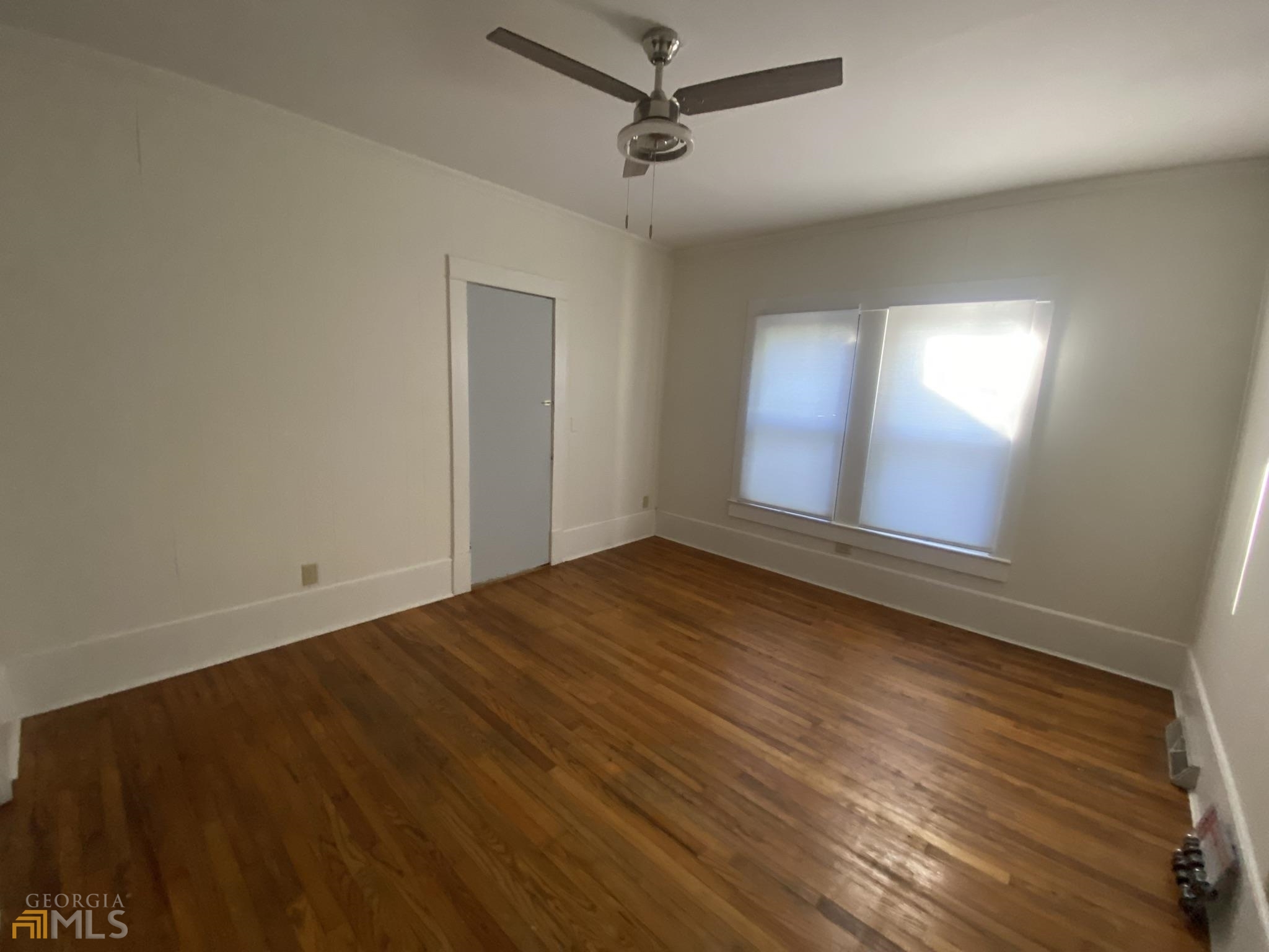 an empty room with wooden floor and windows