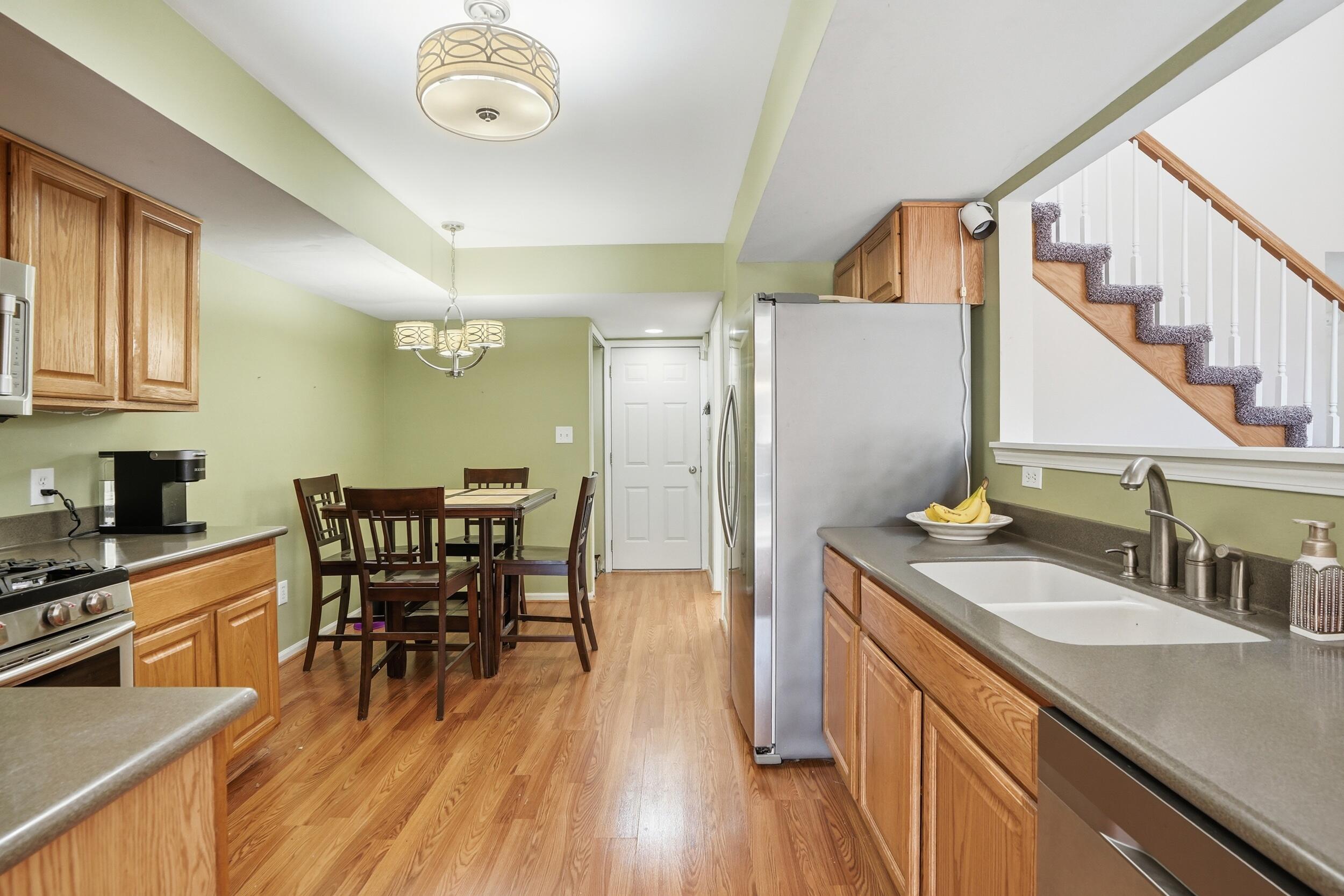 2184 Timberidge Lane Highland, IN 46322 - Photo 5 of 18 a kitchen with stainless steel appliances granite countertop a sink a stove white refrigerator a dining table and chairs with wooden floor