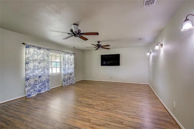 a view of an empty room with window and wooden floor