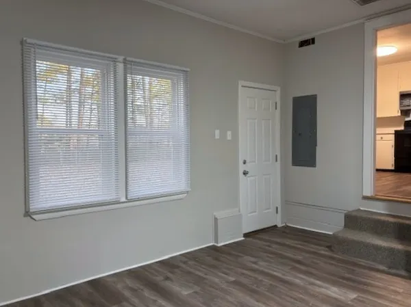 a view of an empty room with wooden floor and a window