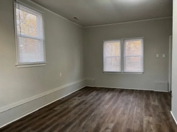 an empty room with wooden floor and windows