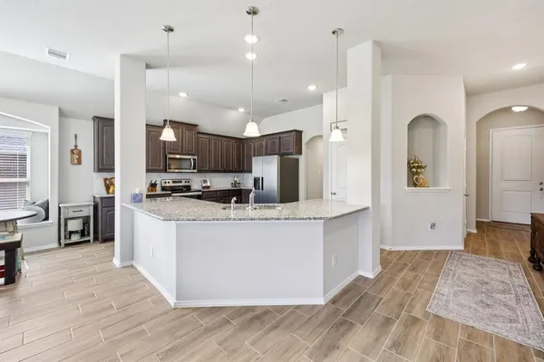a large kitchen with stainless steel appliances kitchen island a large counter top and a wooden floors