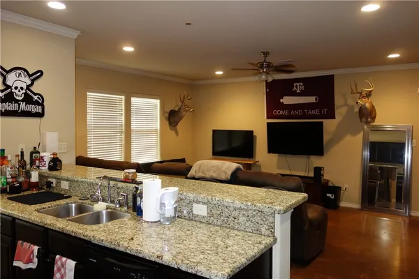 a kitchen with granite countertop kitchen island stainless steel appliances a sink and a living room