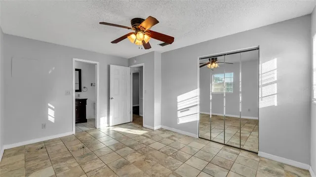 a view of an empty room with window and chandelier fan