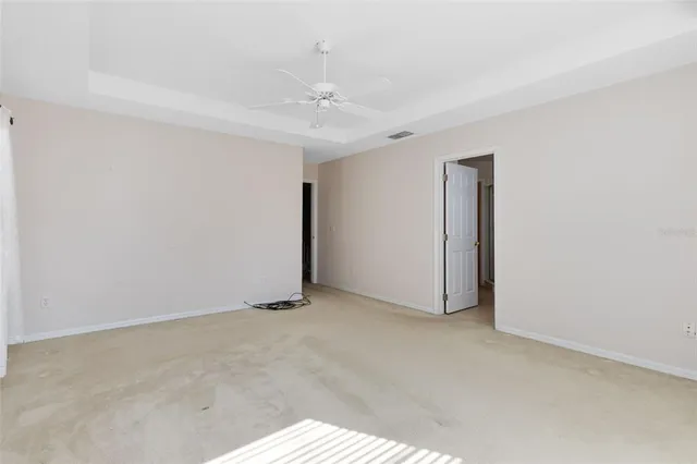 an empty room with a ceiling fan and carpet