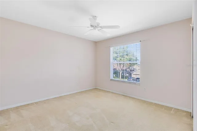 an empty room with a window and a fan