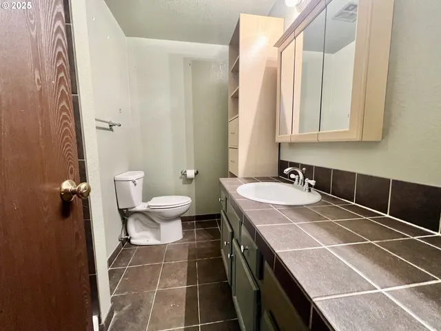 a bathroom with a granite countertop sink a toilet and a mirror