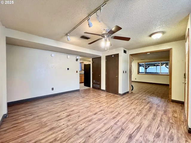 a view of an empty room with window and wooden floor