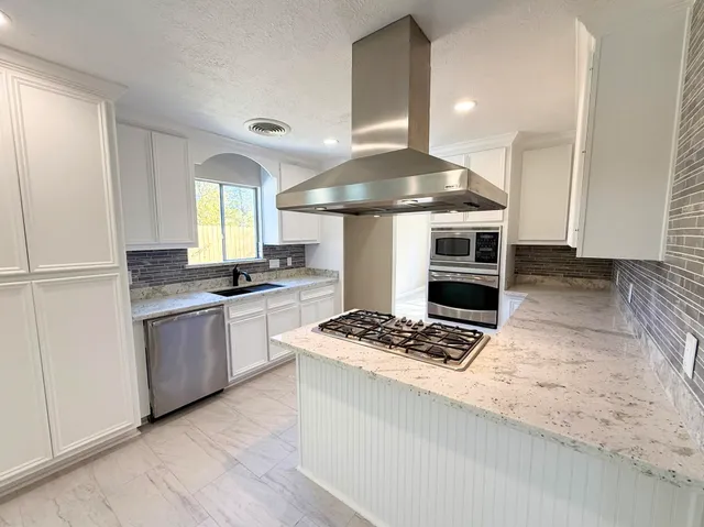 a kitchen with stainless steel appliances granite countertop a stove a sink and a refrigerator