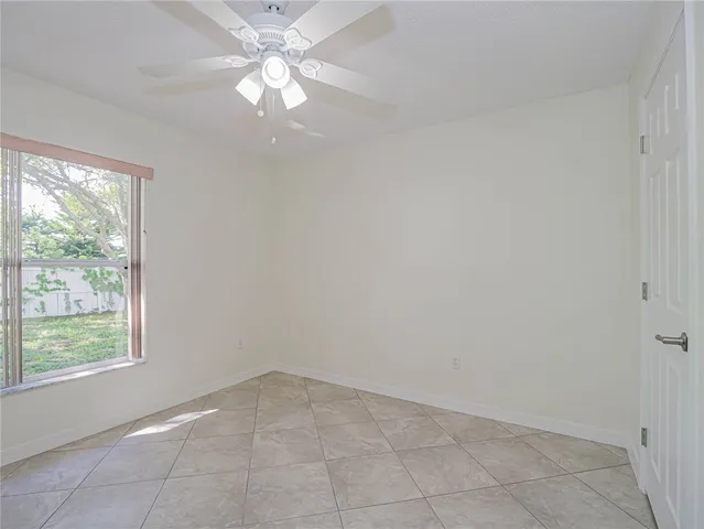 an empty room with a window and a fan