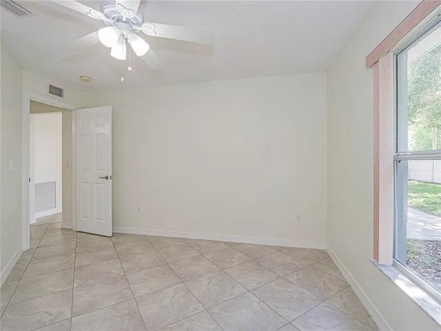an empty room with a ceiling fan and a window