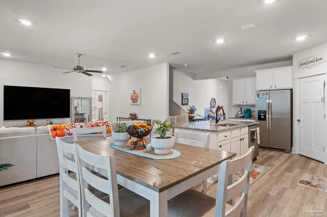 a kitchen with stainless steel appliances a stove a sink a microwave a refrigerator and white cabinets with wooden floor