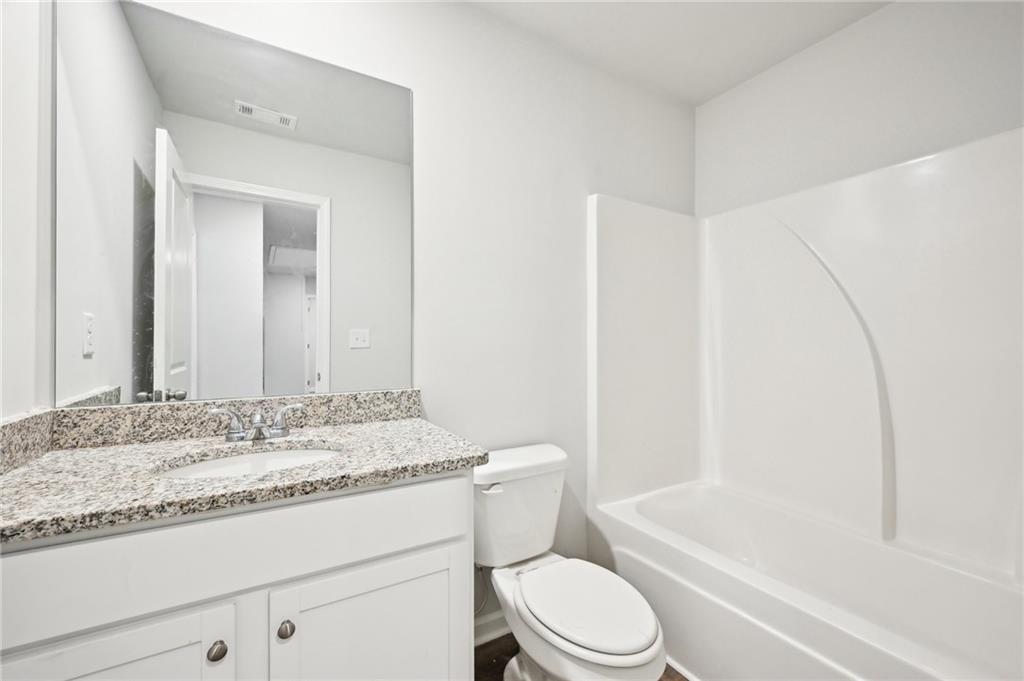 4437 Ben Hill Road Atlanta, GA 30349 - Photo 21 of 40 a bathroom with a granite countertop sink toilet mirror vanity and bathtub