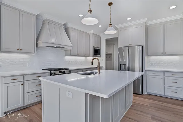 a kitchen with kitchen island a counter space a sink appliances and cabinets