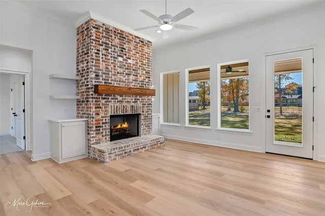 a view of an empty room with wooden floor fireplace and a window