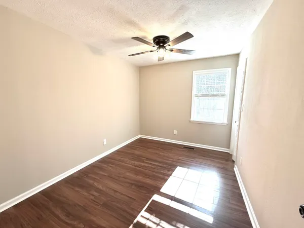 a view of empty room with wooden floor and fan