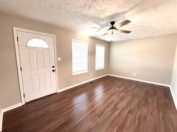 an empty room with wooden floor fan and windows