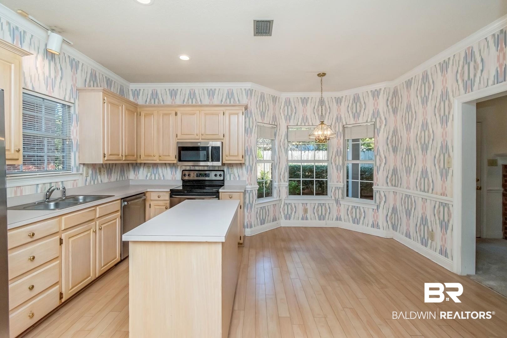 105 McHugh Lane Mobile, AL 36608 - Photo 13 of 30 Kitchen with wallpapered walls, crown molding, light countertops, decorative light fixtures, and appliances with stainless steel finishes