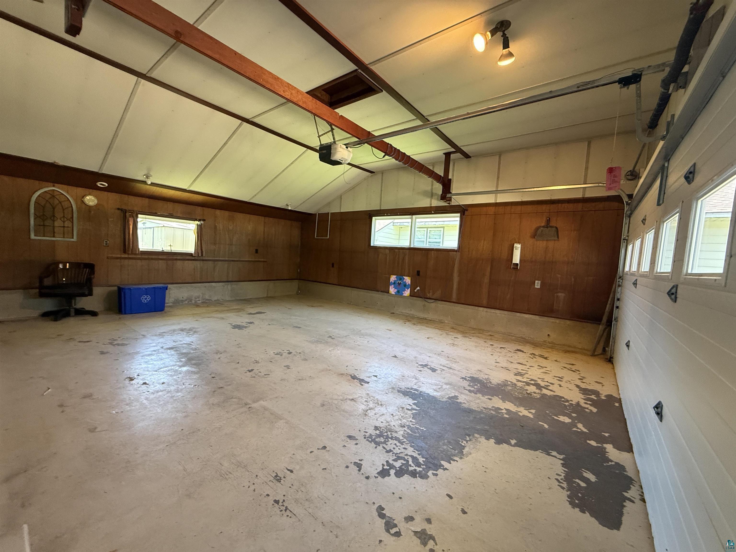 607 3rd Street Northeast Chisholm, MN 55719 - Photo 29 of 32 Spacious garage featuring a concrete floor, wood-paneled walls, and an overhead garage door