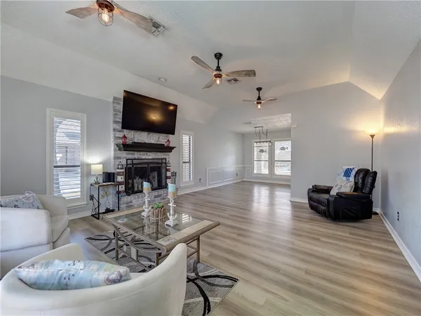 an empty room with fireplace chandelier fan and windows