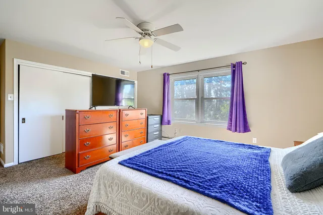 a bedroom with a bed and a flat tv screen on dresser
