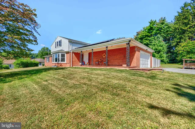 a view of a house next to a big yard and large trees